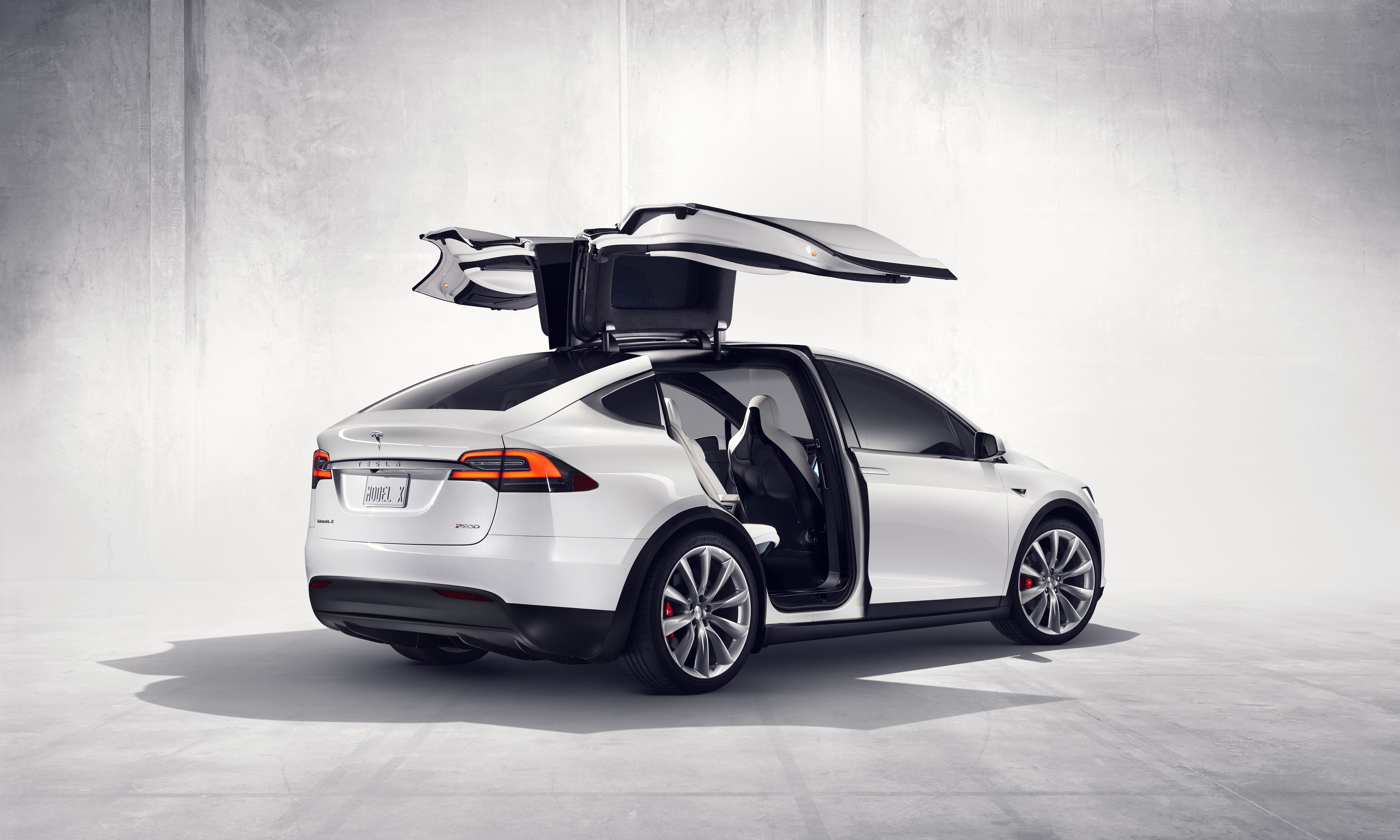 the open falcon wing doors of the white Tesla Model X
